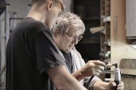 man training apprentice in shop.