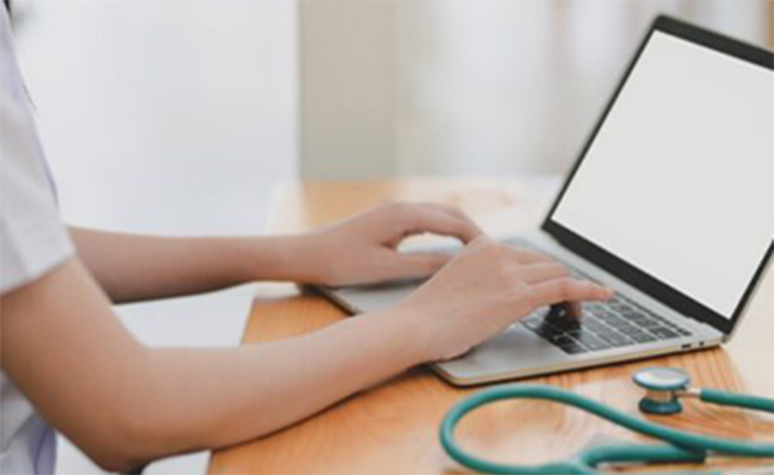 Woman working on laptop with stethoscope.