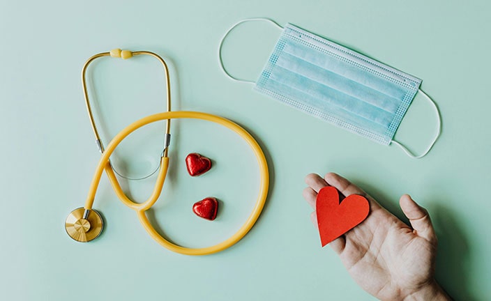 Medical stethoscope and mask composed with red foiled chocolate hearts.