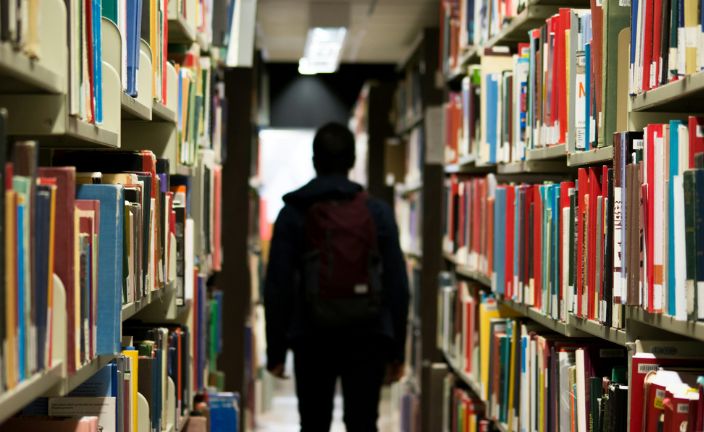 student standing among library shelves.