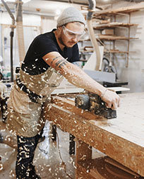 Woodworker sanding a table-leg.