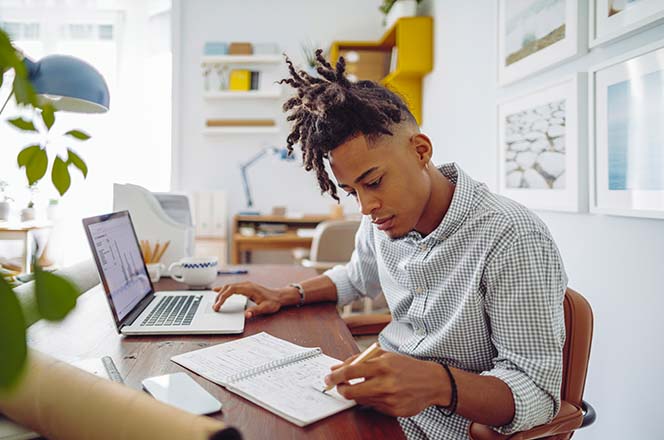 Man taking notes during an online course.
