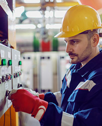 Manufacturing worker operating a machine switchboard.