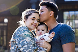 Military family happily smiling with their newborn child.