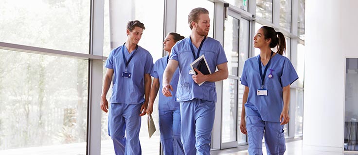 Hospital workers in scrubs walking.