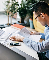 man sitting at a desk with papers and a calculator.