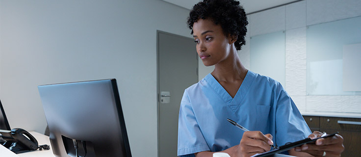medical records technician reading computer screen and taking notes