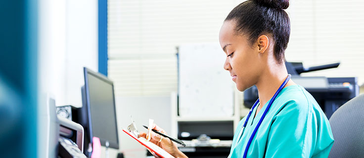 health professional looking at a chart in front of a computer.