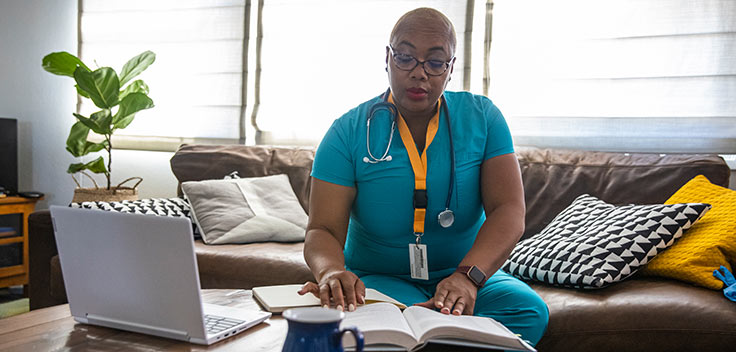 Healthcare worker reading a book and studying while taking online classes.