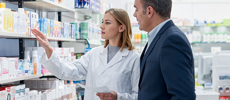 Pharmacist technician organizing shelves within a pharmacy.