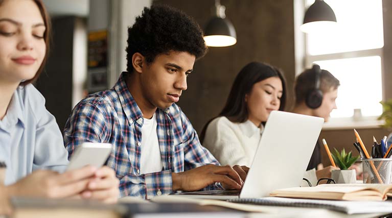 young adults sitting at a table doing work.
