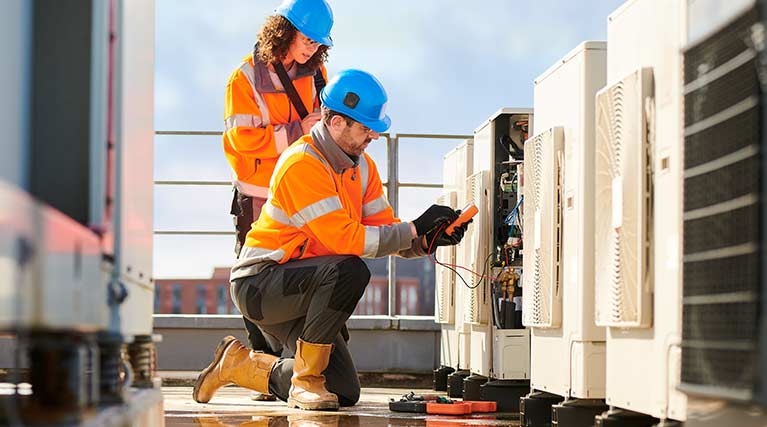 Two HVAC workers installing a commercial A/C.