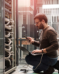 IT technician using laptop in server room