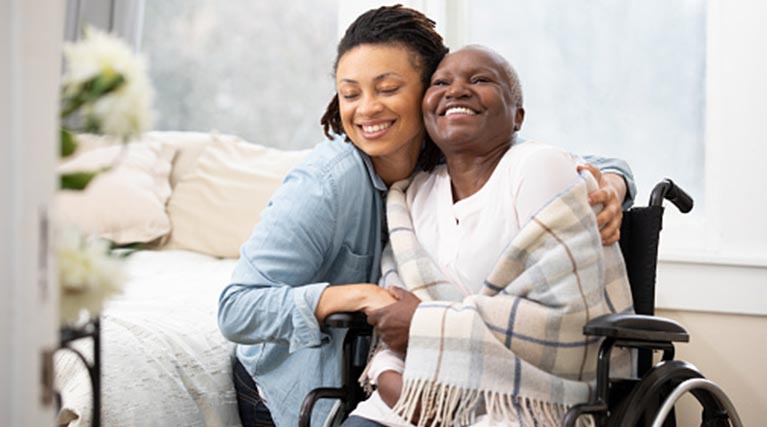 caregiver hugging patient in wheelchair.