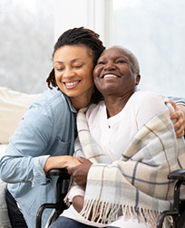 caregiver hugging patient in wheelchair.
