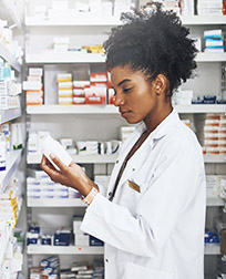 pharmacist reading prescription bottle in pharmacy