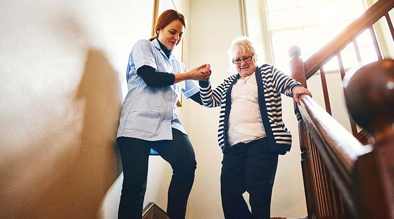occupational therapist helping patient down stairs.
