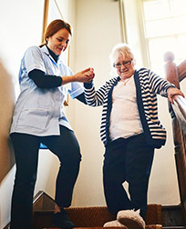 occupational therapist helping patient down stairs.